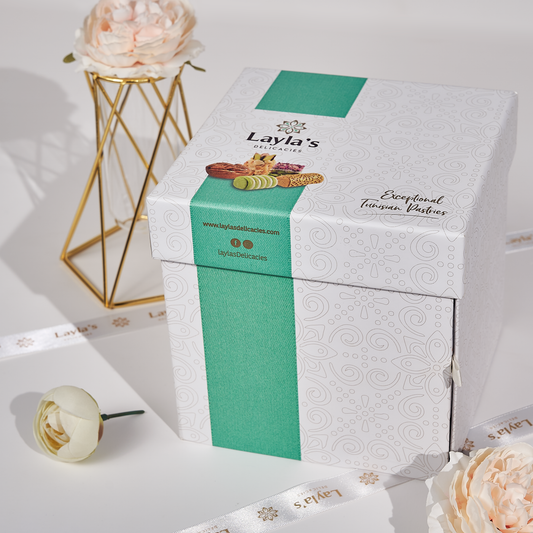 Layla's Delicacies 46 pieces Appreciation gift box presented on a counter next to flowers and a premium ribbon