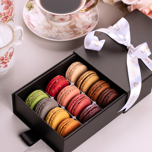 Gift box of premium french macarons with a white ribbon on a light background