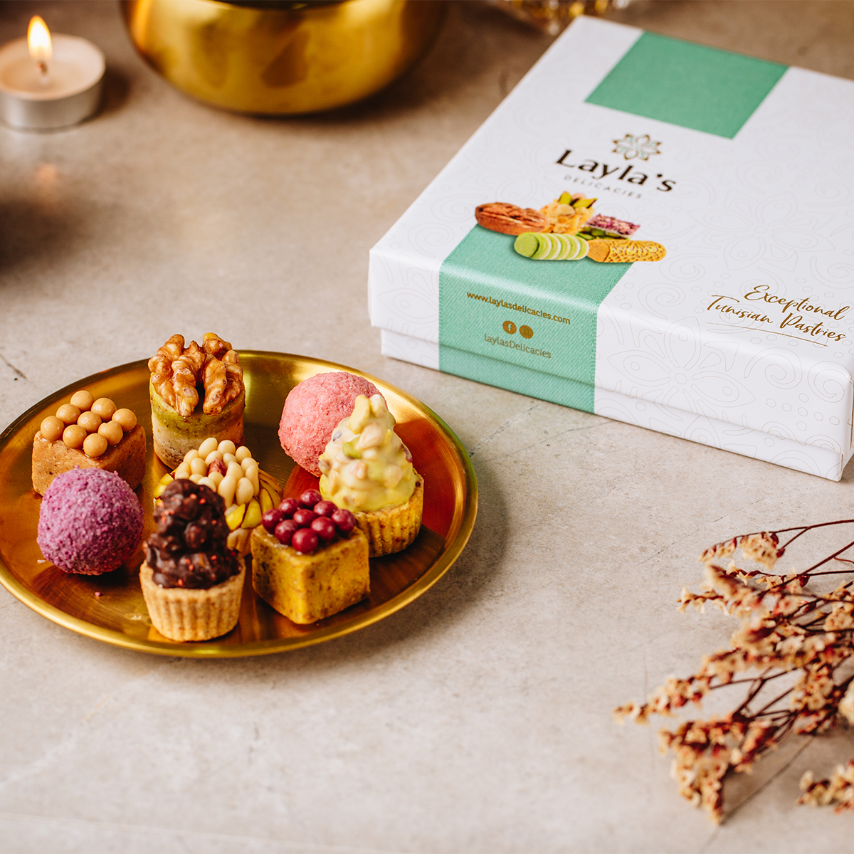 Assorted pastries on a gold plate with Layla's Delicacies premium gift box in the background