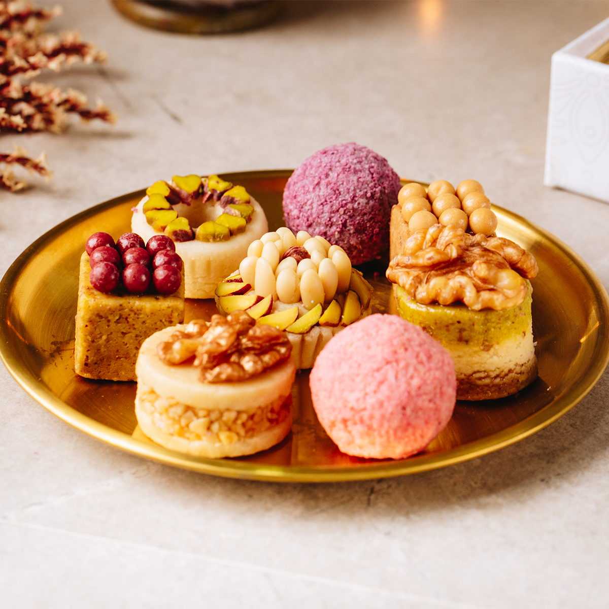 Assorted small handmade pastries on a gold plate with a neutral background
