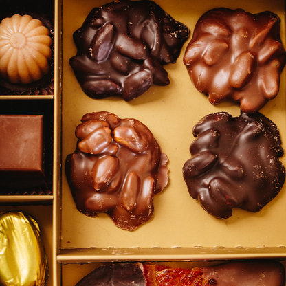 Assorted chocolates including dark pistachio roche and milky pistachio roche pieces with nuts on a gold tray.